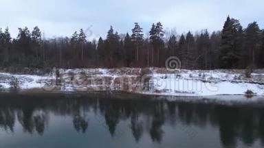 空中观景。 冬林中的湖泊.. 在多云的冬季天气中飞过一个没有结冰的湖。 五彩缤纷的风景，霜冻的前夜